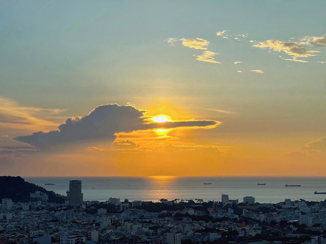 A coastal cityscape at sunset with buildings along the waterfront.