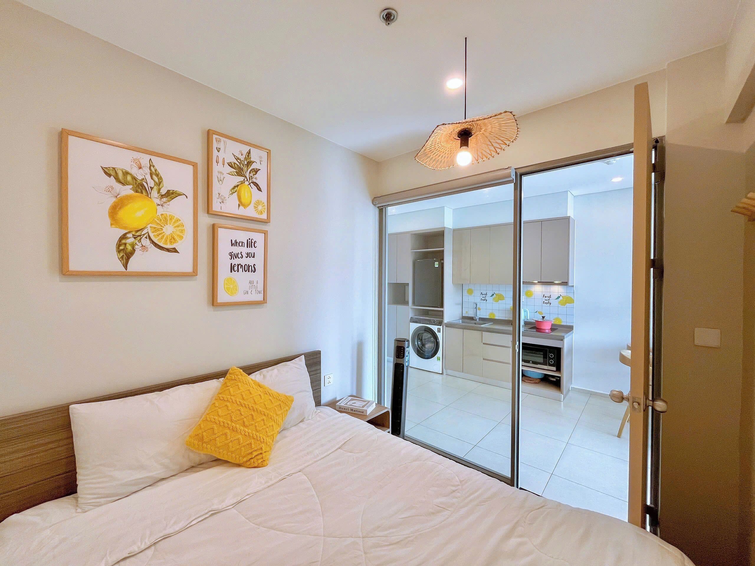 Une chambre à coucher avec un lit, un oreiller jaune et un mur orné de tableaux encadrés.
