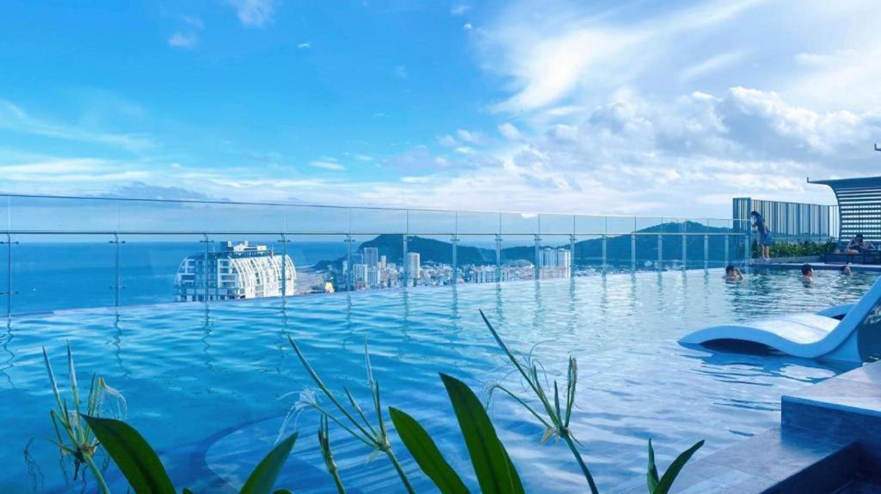 Una piscina infinita con vistas despejadas a un paisaje urbano y montañas al fondo.