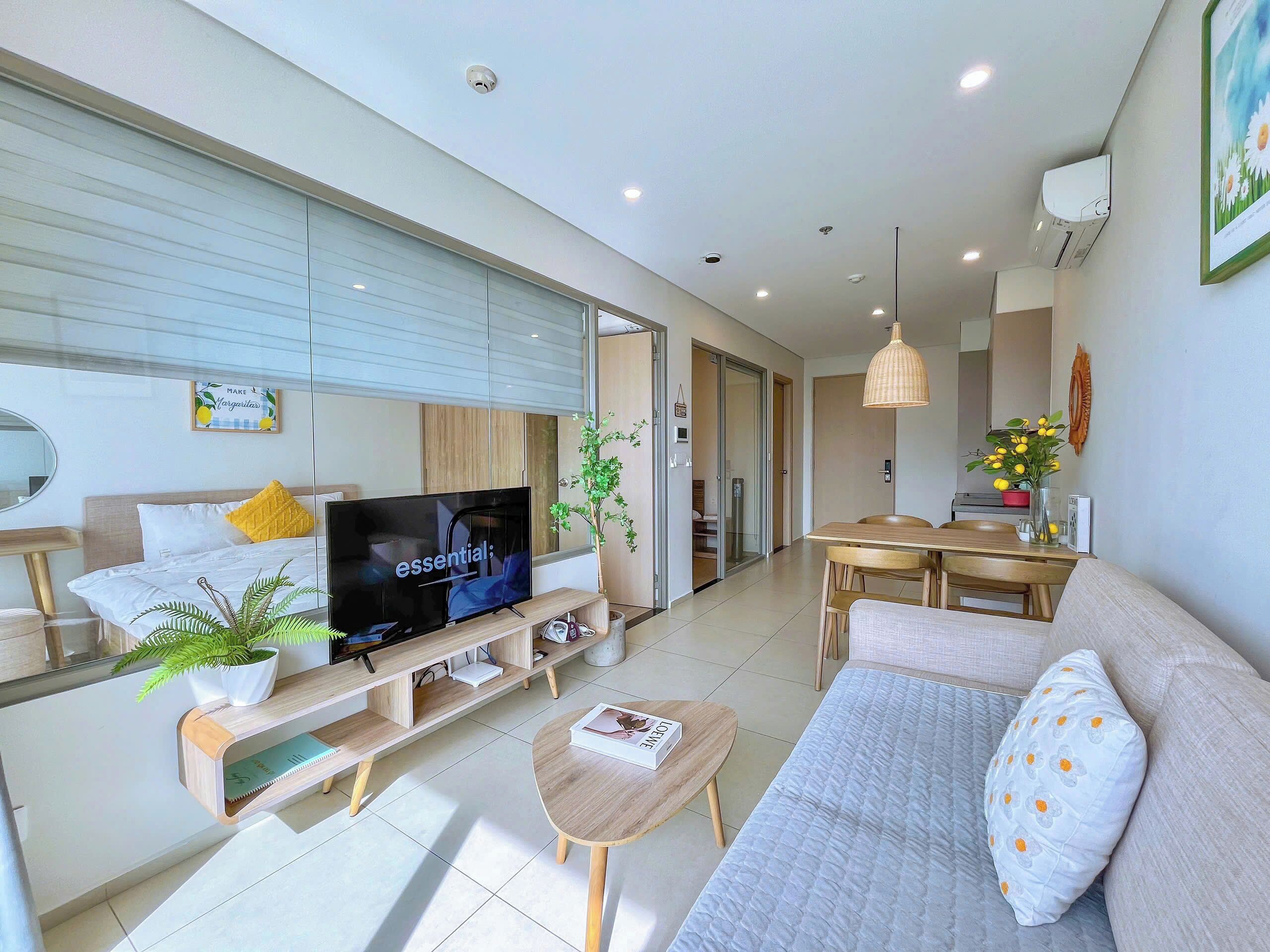 A modern living room with a flat-screen TV, sofa, coffee table, and dining area.