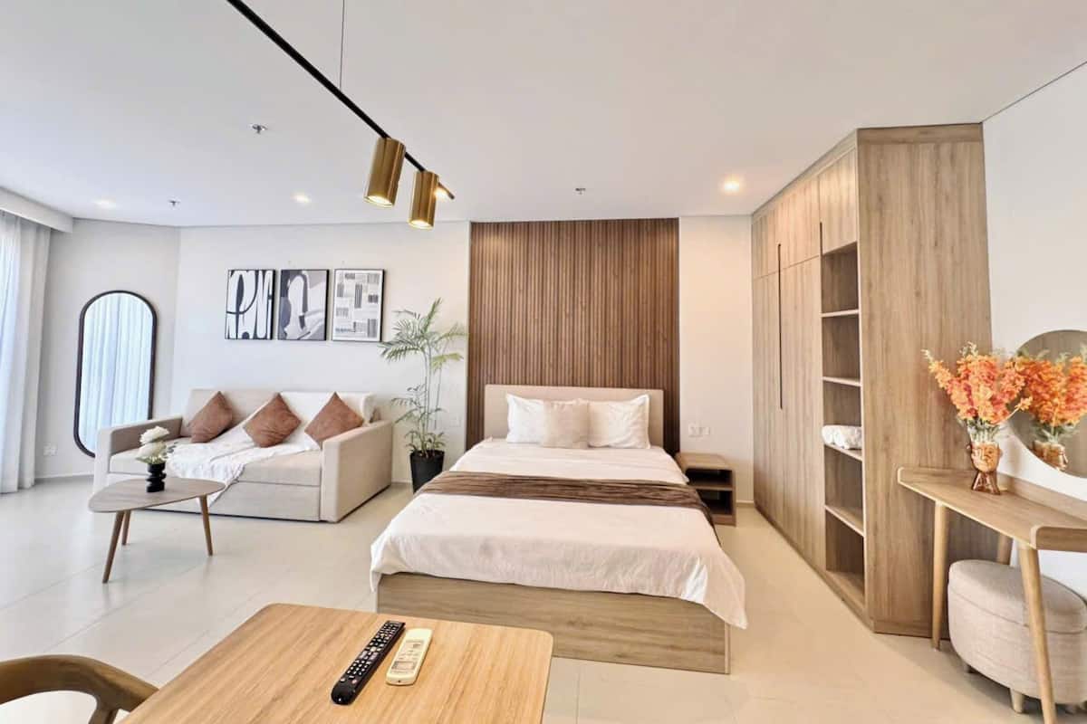 A modern hotel room with a bed, a sofa, a desk, and a wardrobe.