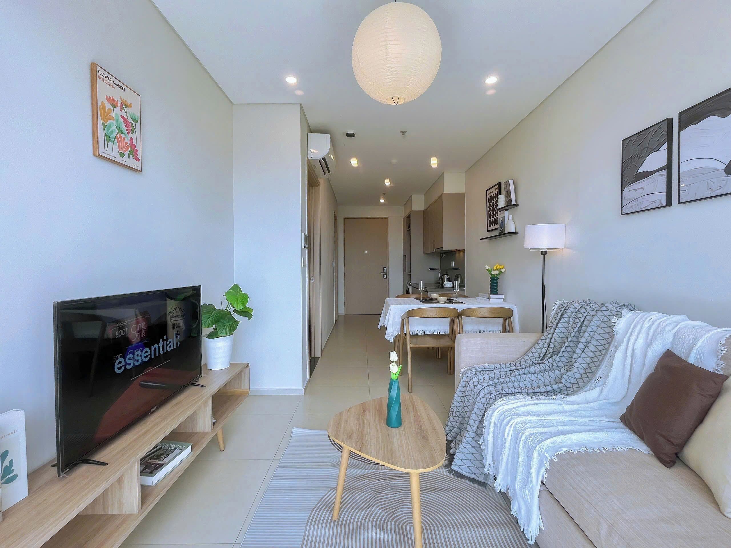 Un salon moderne avec un téléviseur à écran plat, un canapé, une table basse et un coin repas à l’arrière-plan.