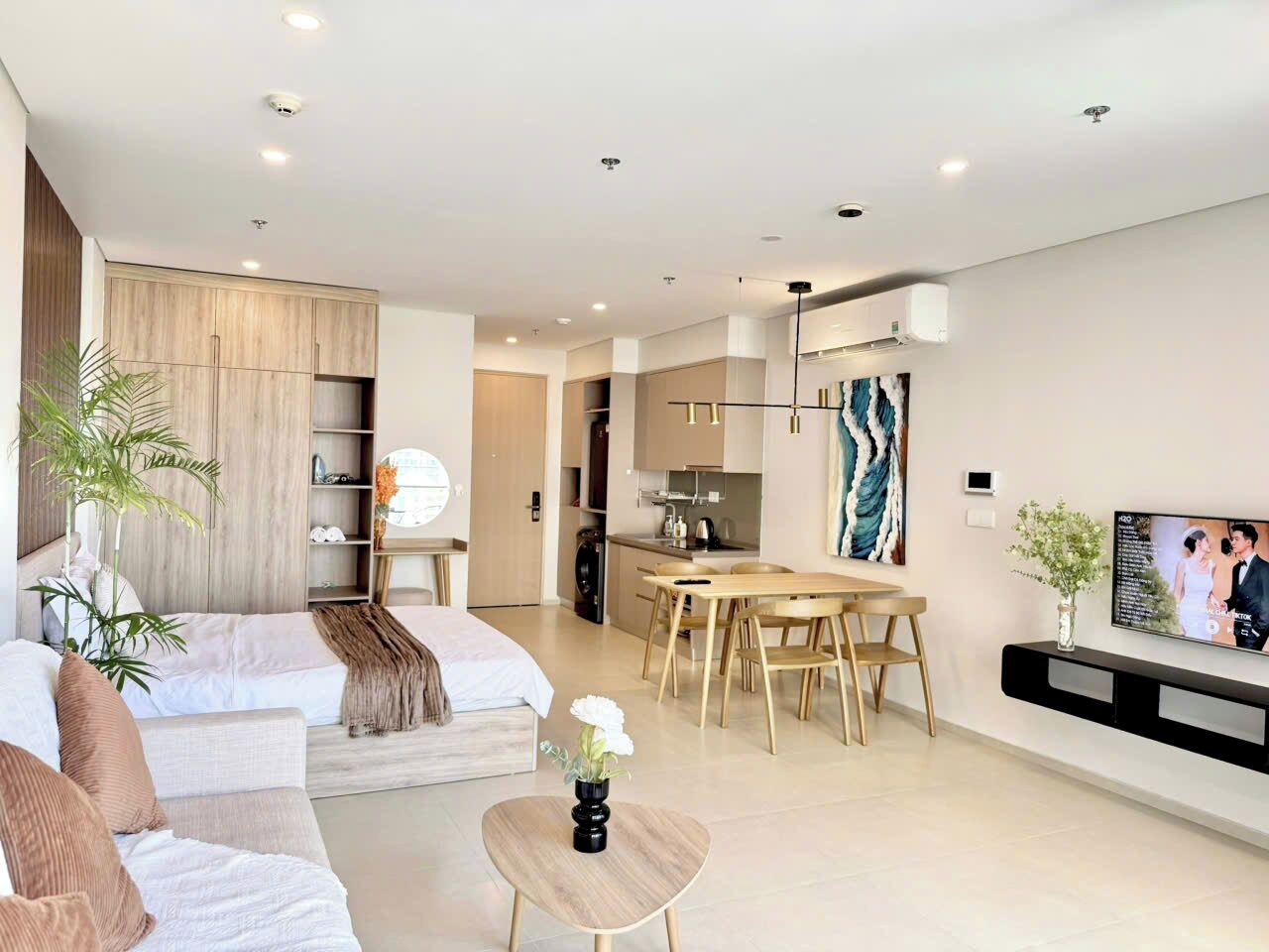 Una sala de estar moderna con un sofá, una mesa de centro, una zona de comedor con una mesa y sillas, y una cocina al fondo.