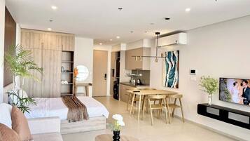 Una sala de estar moderna con un sofá, una mesa de centro, una zona de comedor con una mesa y sillas, y una cocina al fondo.