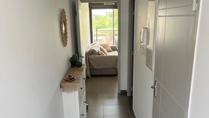 A hallway leading to a bedroom with a bed, a small table, and a decorative wall piece. - Seemingly cosy, close to the beach and in the heart of the golf course (Saint-Cyprien)