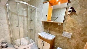 A bathroom with a glass-enclosed shower, a sink, and a toilet. - N-V Suites (Istanbul)