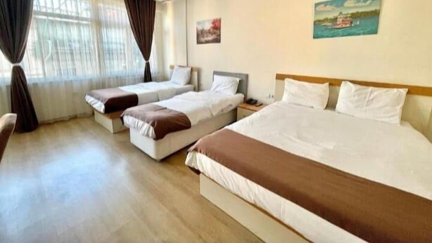 A hotel room with three beds, a large window with curtains, and a painting on the wall. - N-V Suites (Istanbul)