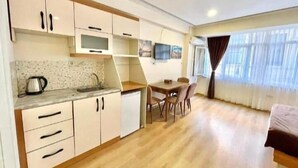 A compact kitchen with a dining area, wooden flooring, and a window with curtains. - N-V Suites (Istanbul)