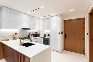 A modern kitchen with white cabinetry, a central island with a sink, and built-in appliances.