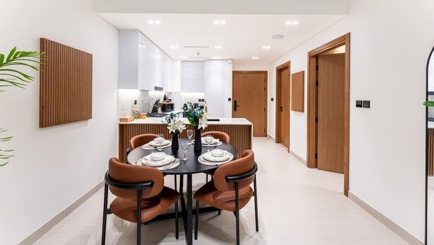 Un espace repas moderne avec une table ronde prévue pour quatre personnes, entourée de lambris en bois et agrémentée d’une plante en pot.