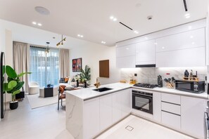 Eine moderne Küche mit weißen Schränken, einer zentralen Kochinsel und einem Essbereich mit einer Couch und einem Couchtisch.