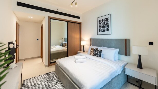 Ein modernes Hotelzimmer mit einem großen Bett, Nachttischen, einem Spiegel und einer Deckenleuchte.