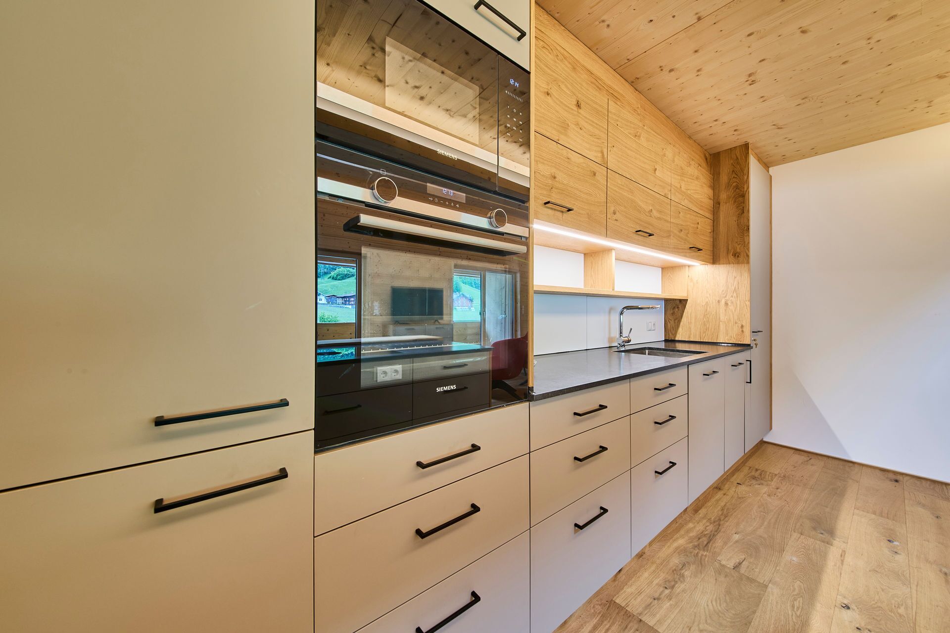 A modern kitchen with wooden cabinetry, a built-in oven, and a stainless steel countertop.