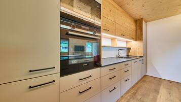 A modern kitchen with wooden cabinetry, a built-in oven, and a stainless steel countertop.
