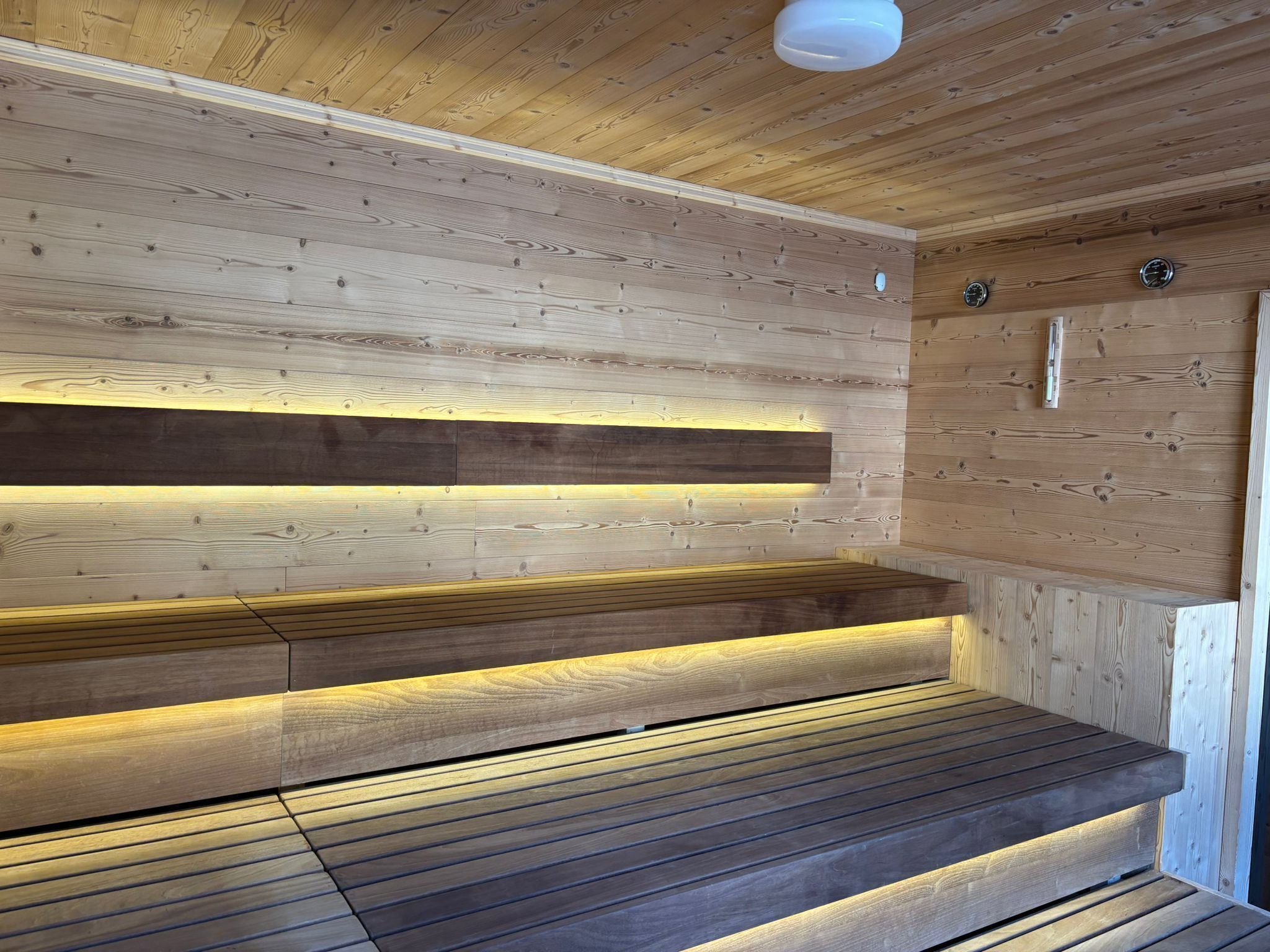 A wooden sauna with benches and a sloped ceiling.