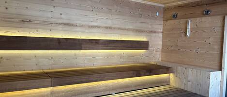 A wooden sauna with benches and a sloped ceiling.