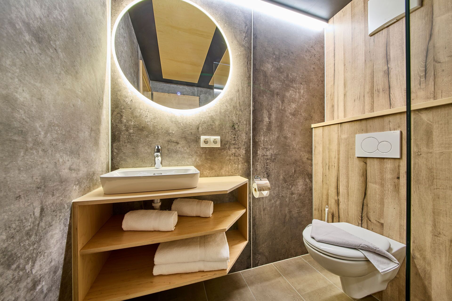 Une salle de bain moderne avec un meuble-lavabo en bois, un évier, des toilettes et un miroir.