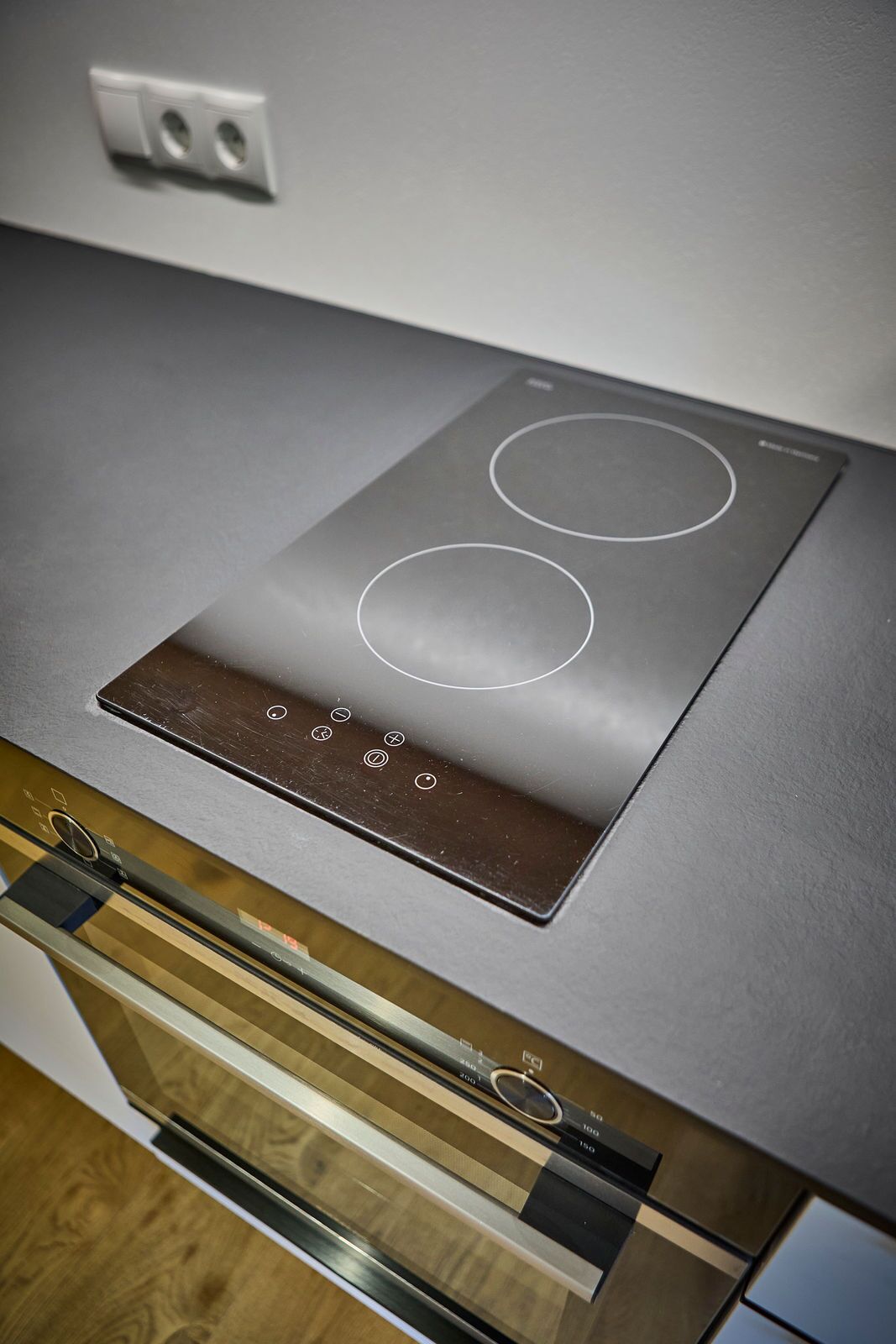 A modern kitchen with a built-in induction cooktop and a stainless steel oven.