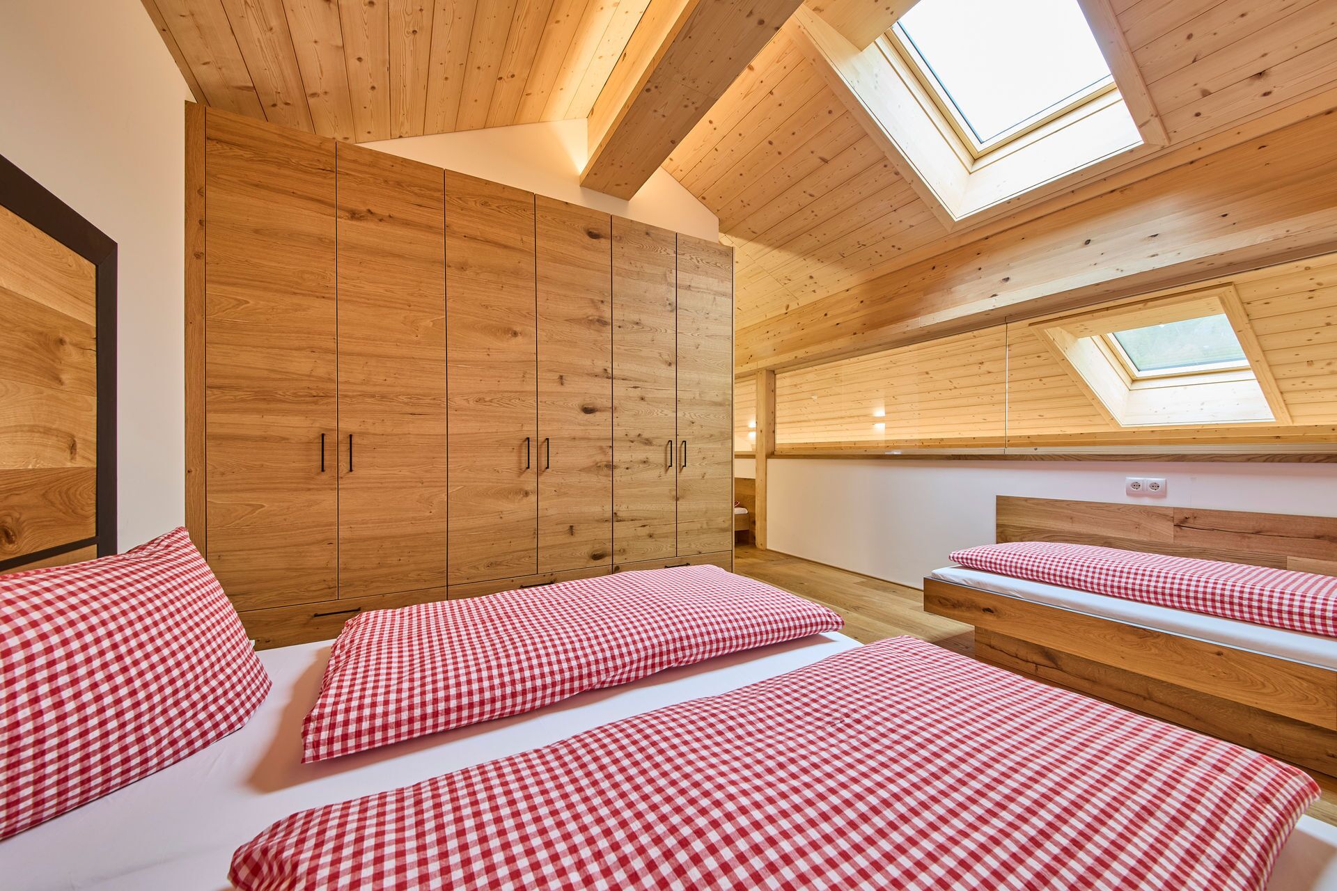 A bedroom with wooden walls, a large wardrobe, and skylights.