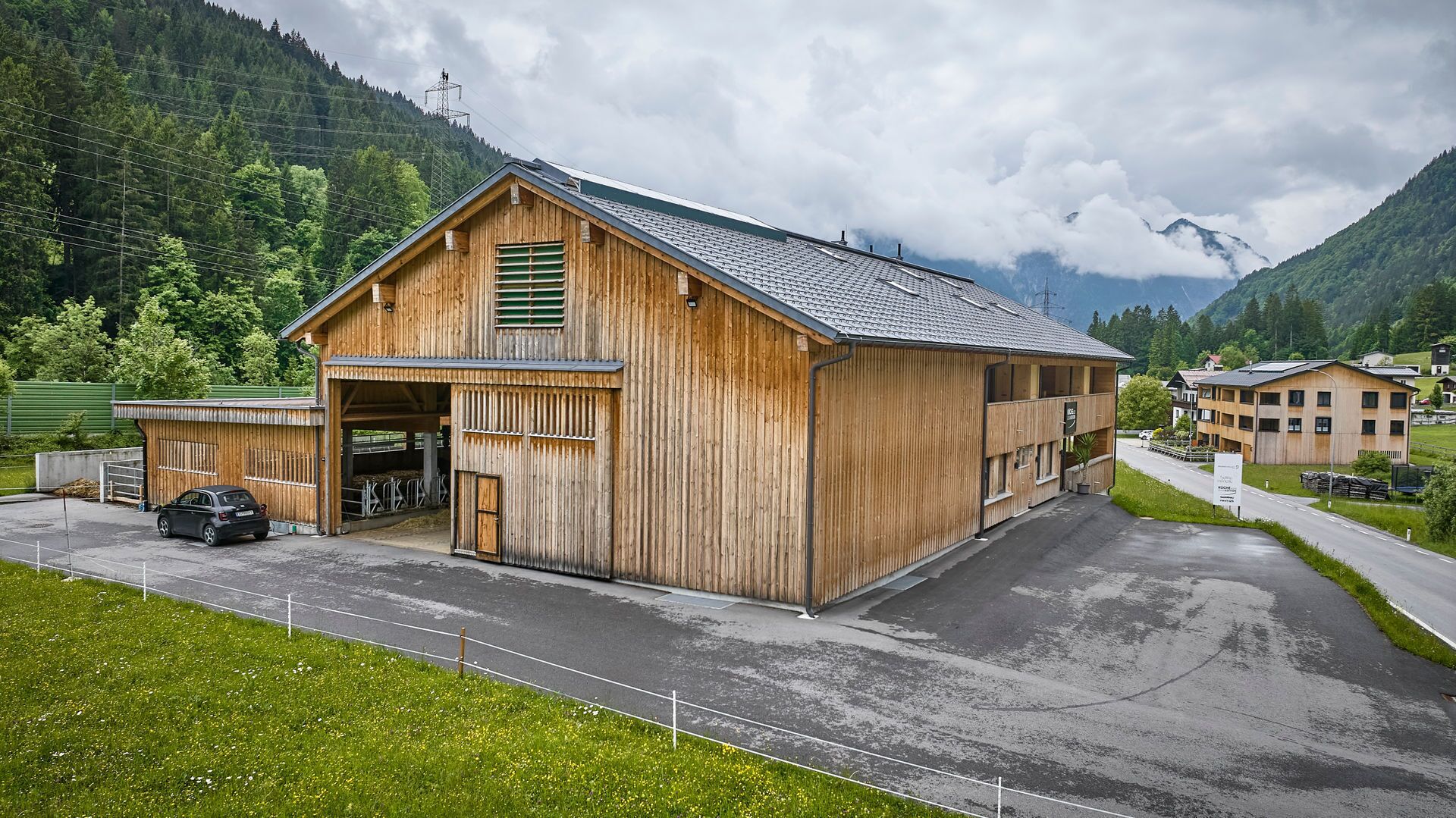 A wooden barn-style building with a sloped roof, large windows, and a covered entrance.