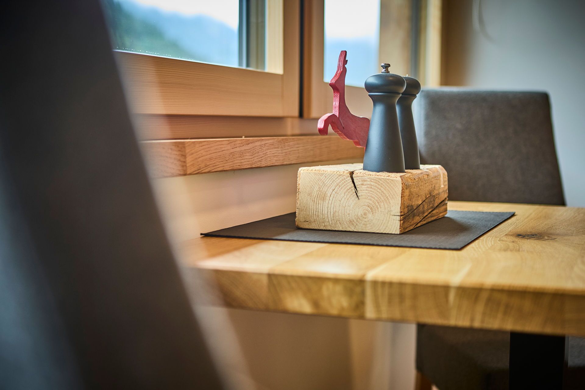 Une table en bois sur laquelle sont posés un salier et un poivrier, le tout sur un tapis noir.