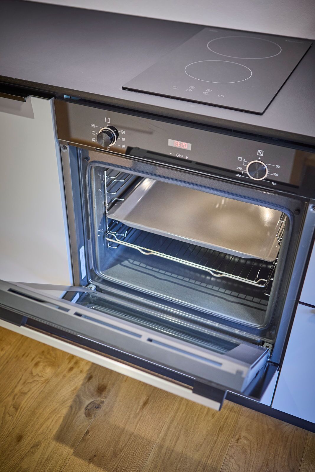 An open oven with a digital clock displaying 13:20.