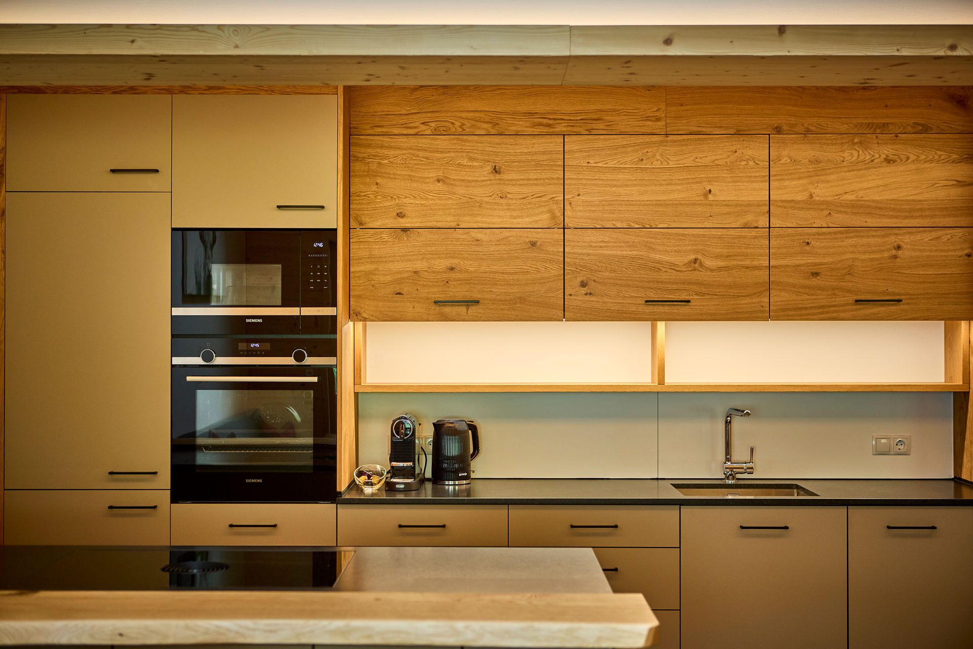 A modern kitchen with wooden cabinets, stainless steel appliances, and a black countertop.