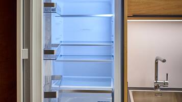 Un refrigerador abierto con varios estantes, un dispensador de agua incorporado y un lavamanos de acero inoxidable.