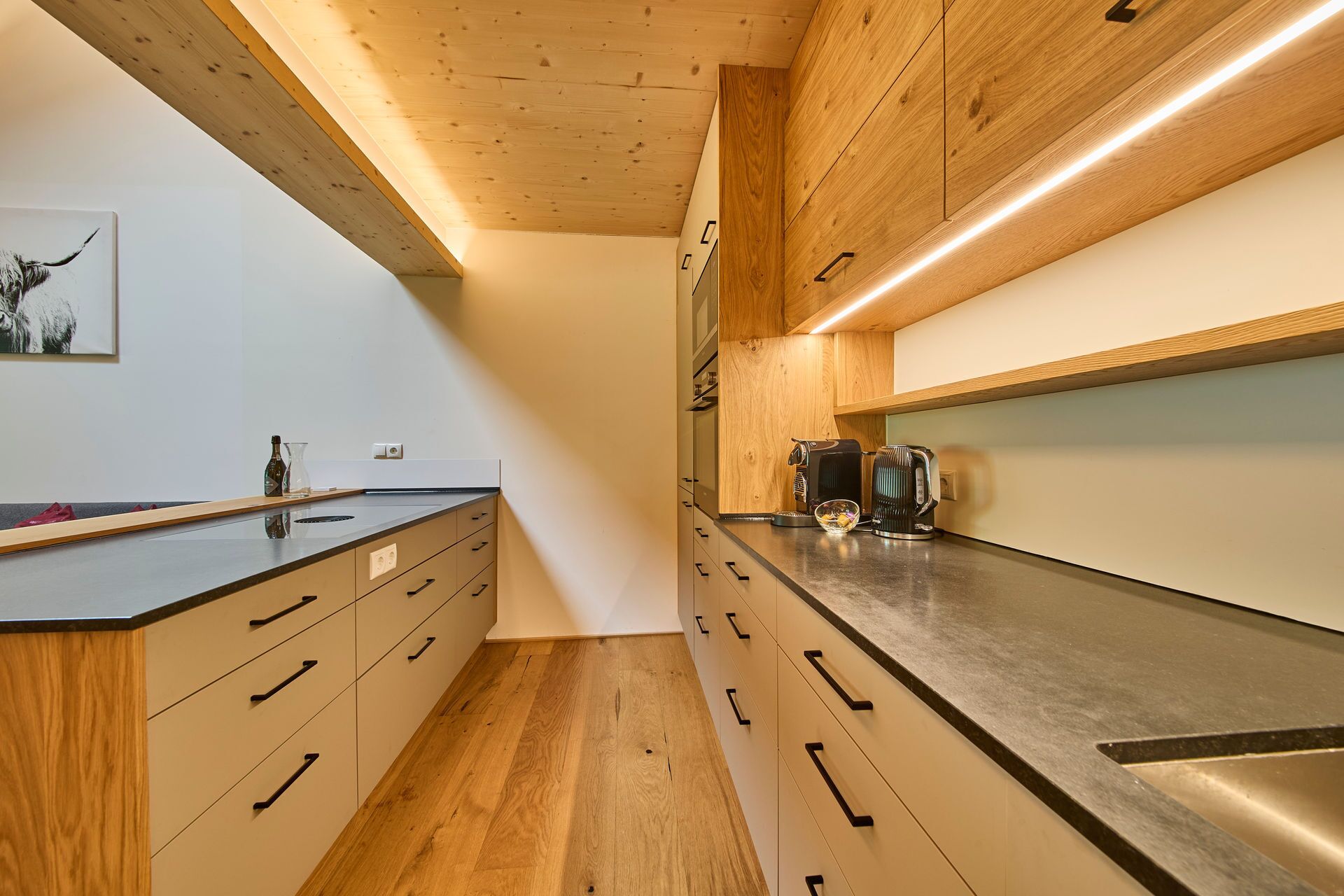 Una cocina moderna con armarios de madera, encimera negra y electrodomésticos de acero inoxidable.