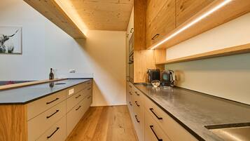 Una cocina moderna con armarios de madera, encimera negra y electrodomésticos de acero inoxidable.