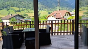 A wooden deck with wicker furniture and a view of a mountainous landscape. - Bocks Apartments 53C (Dalaas)