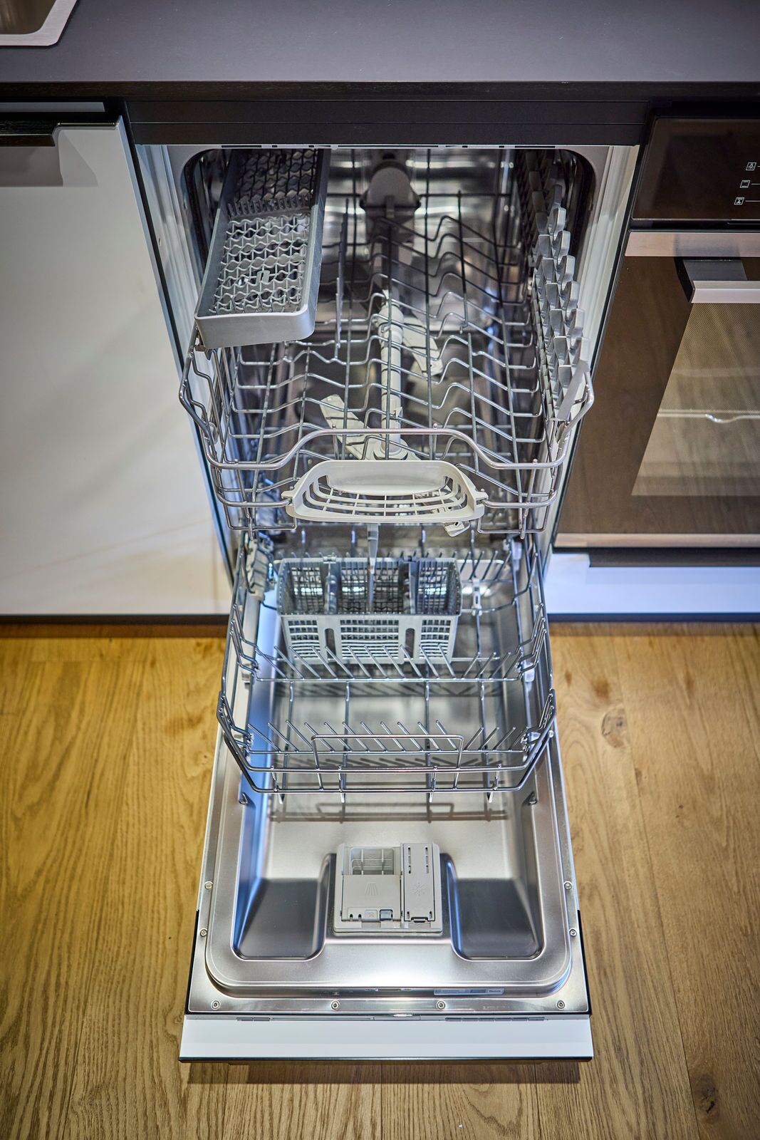 An open dishwasher with multiple racks and a control panel.