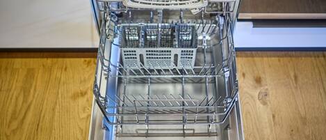 An open dishwasher with multiple racks and a control panel.