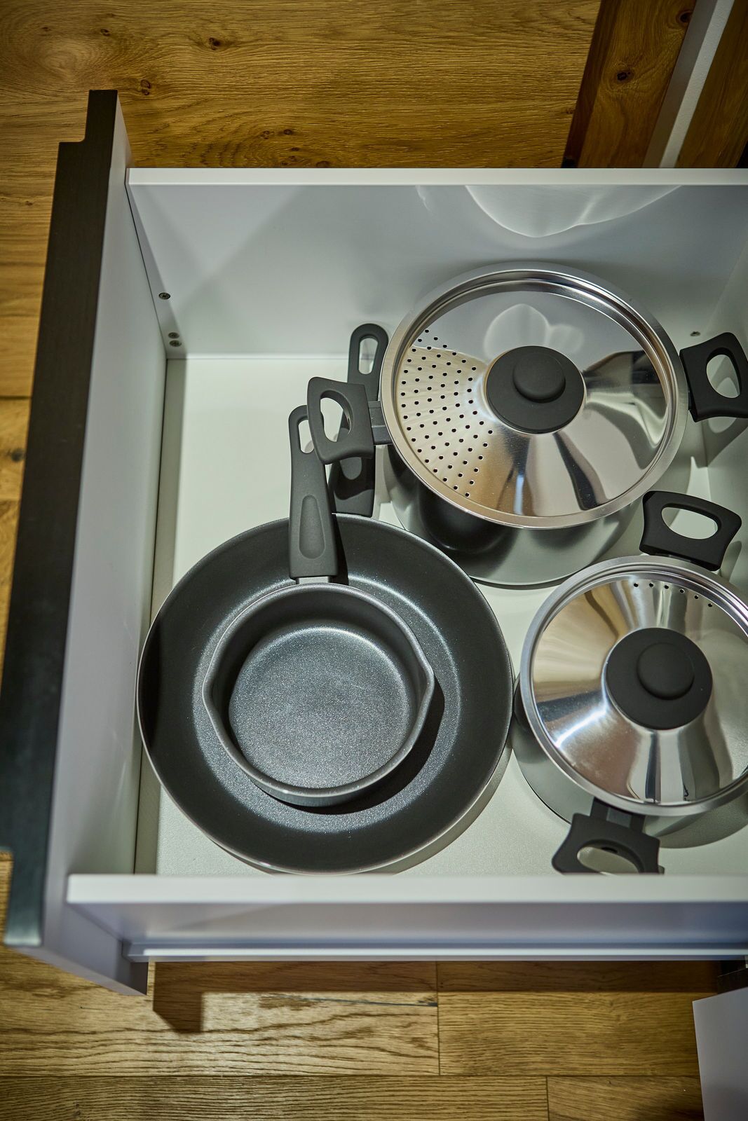 Un tiroir de cuisine contenant trois casseroles et poêles.