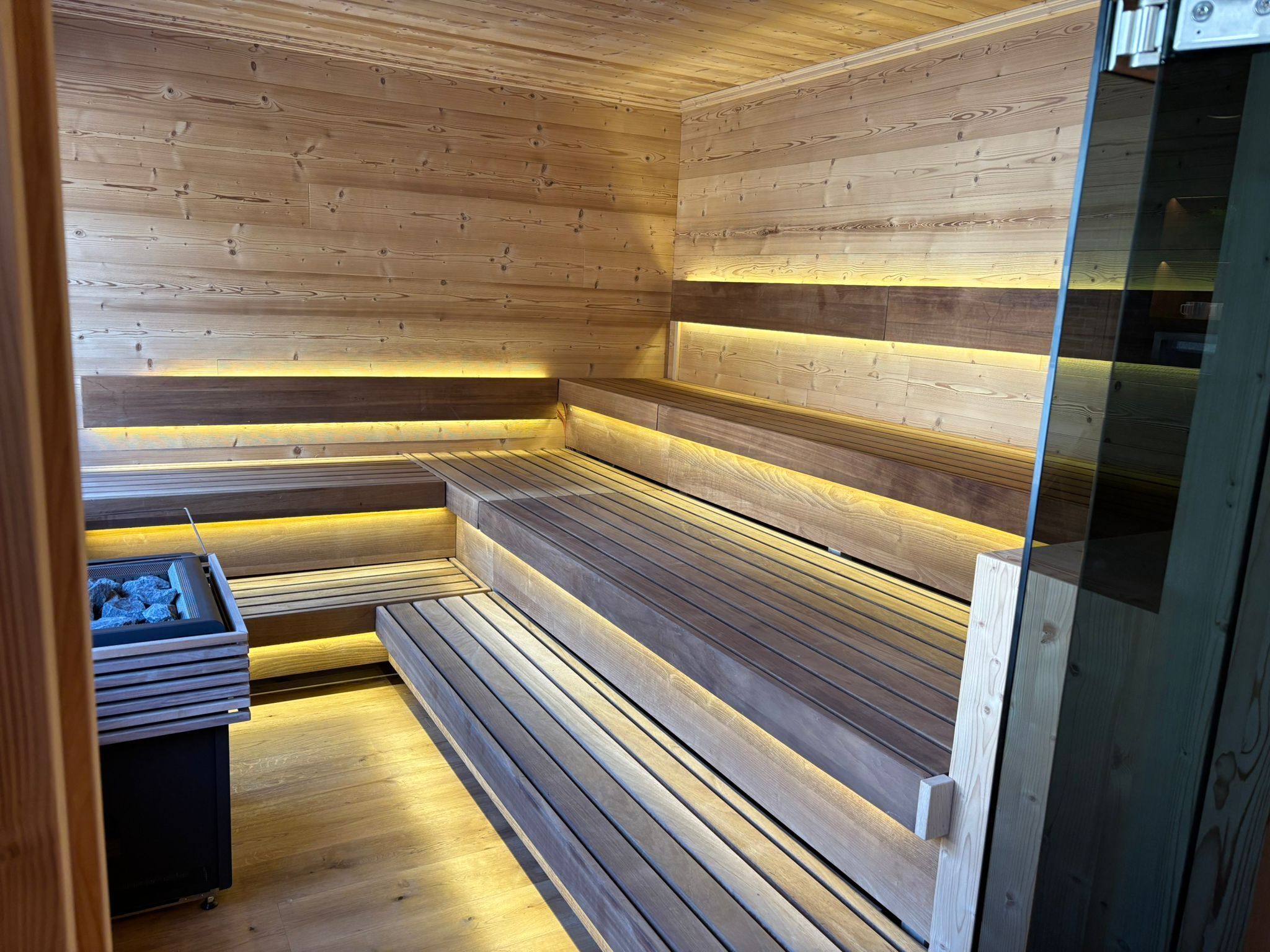 En sauna med træbænke og en glasdør.