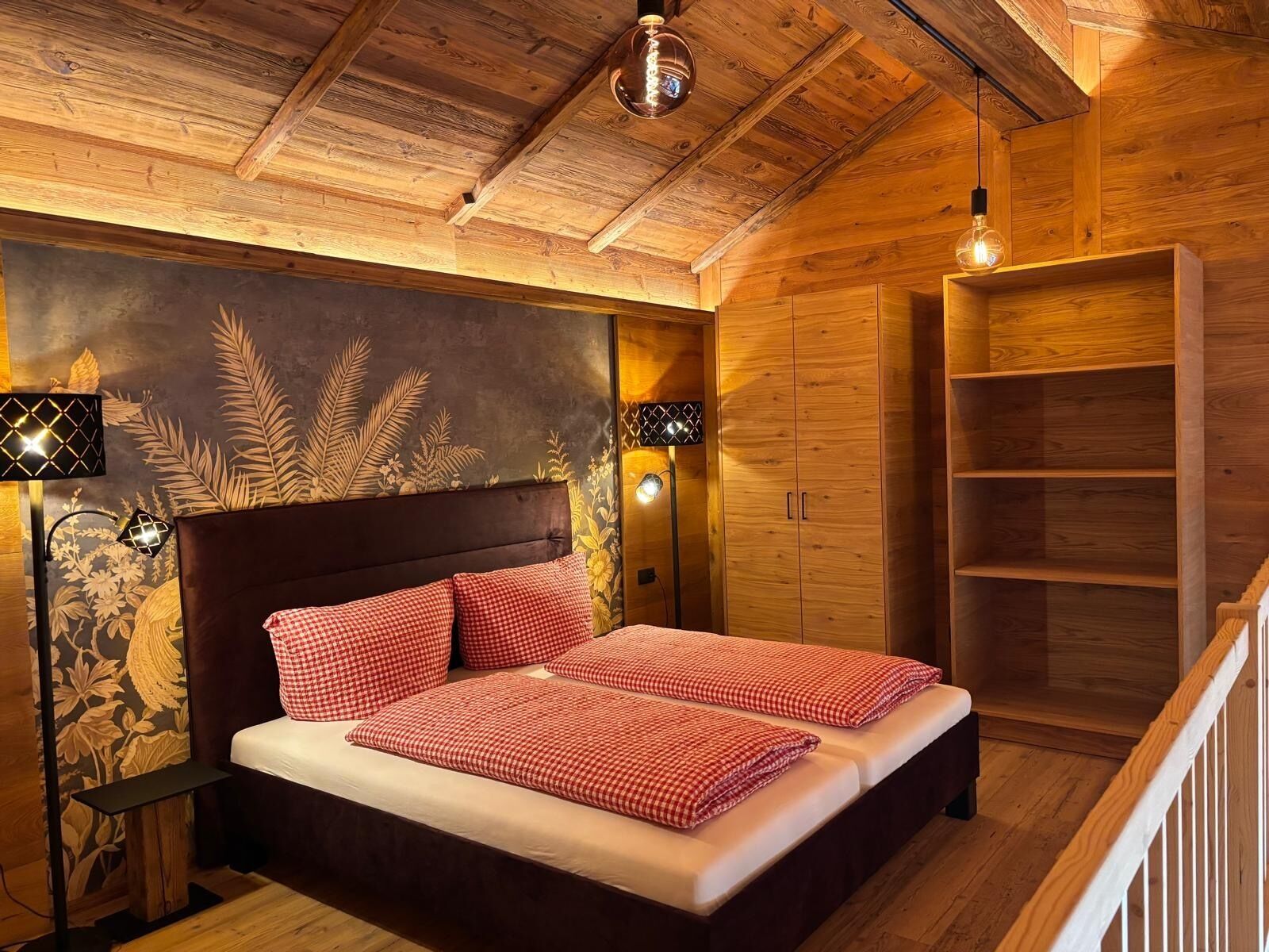 A wooden bedroom with a bed, nightstands, and a wardrobe.