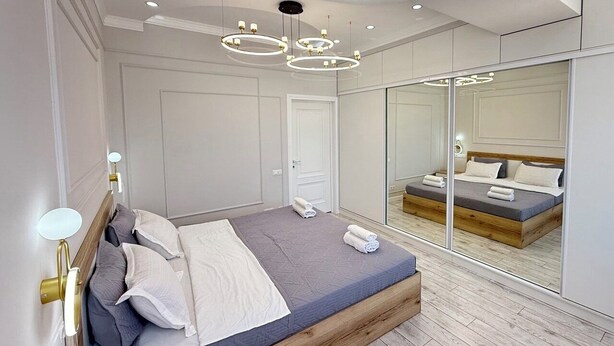 Une chambre moderne avec un grand lit, un miroir et un plancher en bois.