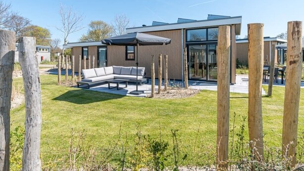 Ein modernes Haus mit einer Terrasse, einem Sofa und einem Tisch.
