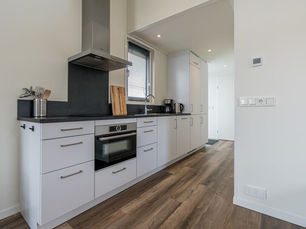 Een moderne keuken met witte kastjes, een zwart aanrecht en een inbouwoven.