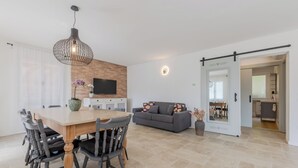 Una sala moderna con una mesa de comedor, sillas, un sofá y una televisión.