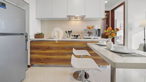 Een moderne keuken met witte kasten, houten accenten, een inbouwfornuis en barstoelen.