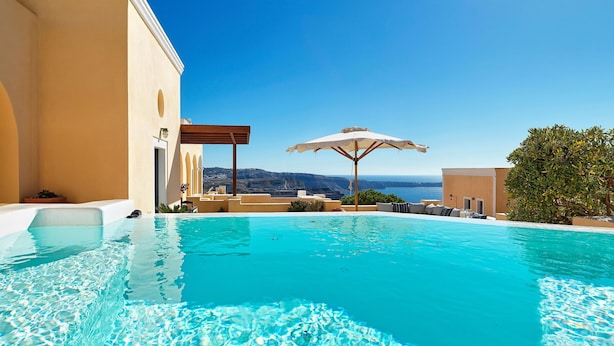 Ein klares, blaues Schwimmbecken mit Blick auf Meer und Berge, eine Pergola mit Sonnenschirm und eine kleine Gartenanlage.