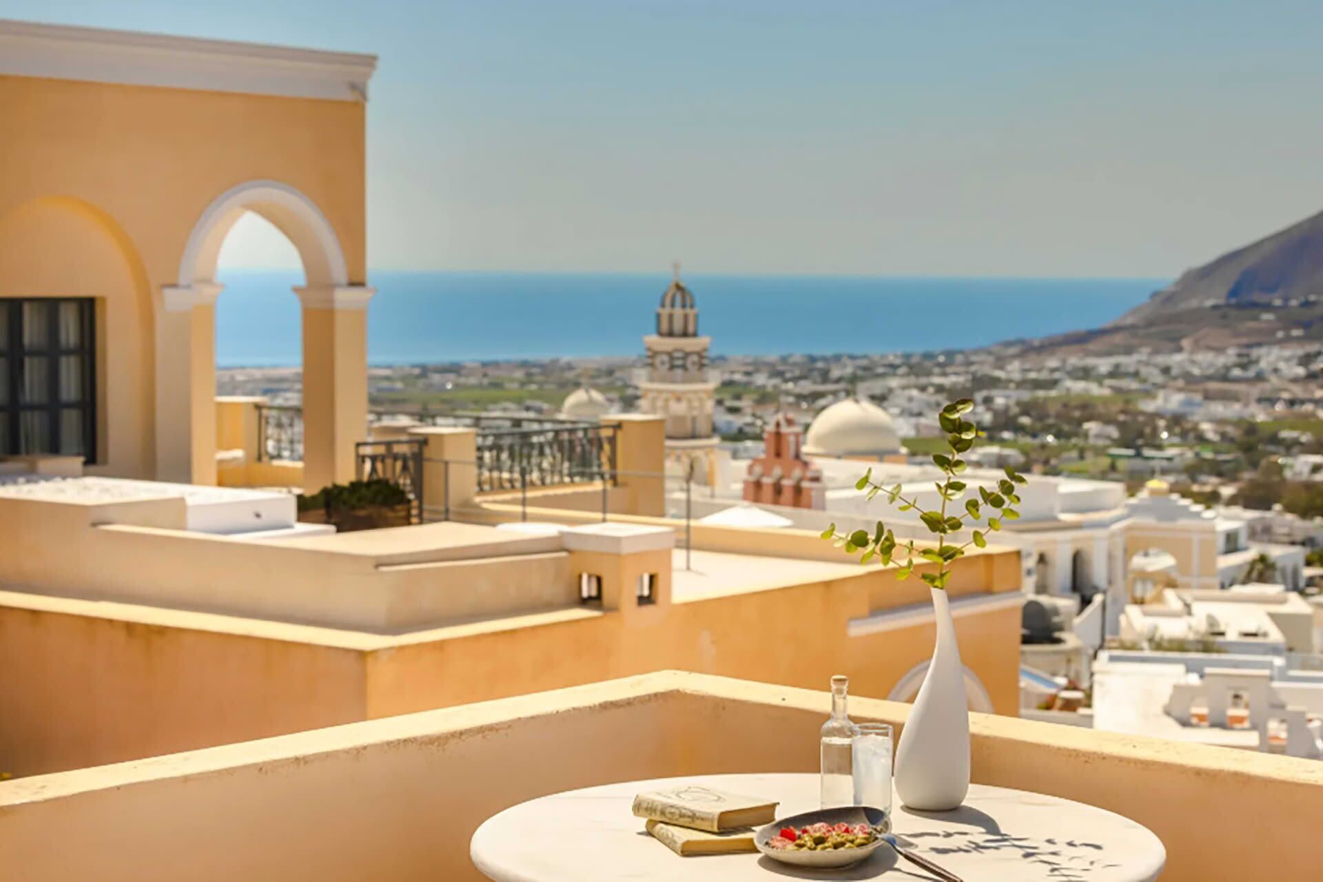 Eine Dachterrasse mit Esstisch, Blick auf eine Stadtlandschaft mit historischer Architektur und Meerblick.