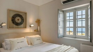 Ein Schlafzimmer mit Bett, Wand-Klimaanlage, Fenster mit Ausblick und einer Wanddekoration.