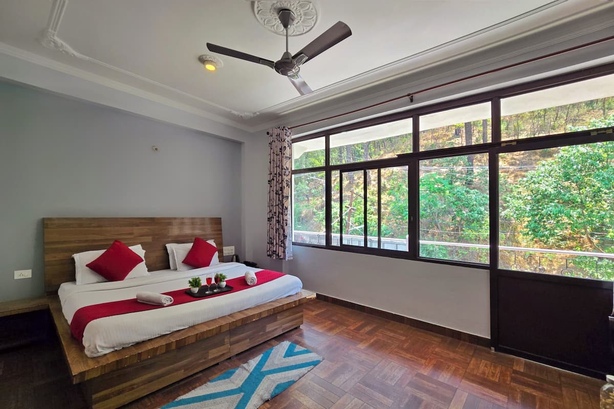 A bedroom with a large window, a ceiling fan, and a wooden bed.