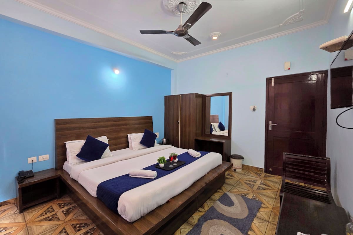 A neatly arranged bedroom with a bed, a wardrobe, a mirror, and a ceiling fan.