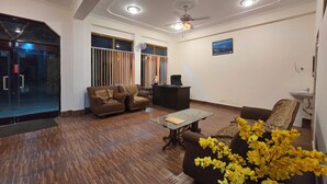 A spacious living room with a wooden floor, a sofa set, a coffee table, and a ceiling fan. - Hotel City Gold - Hotel in Dharamshala (Dharamshala)