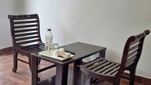 A small, dark wooden table with two matching chairs, a tray with salt, pepper, and a bottle, and a remote control. - Hotel City Gold - Hotel in Dharamshala (Dharamshala)