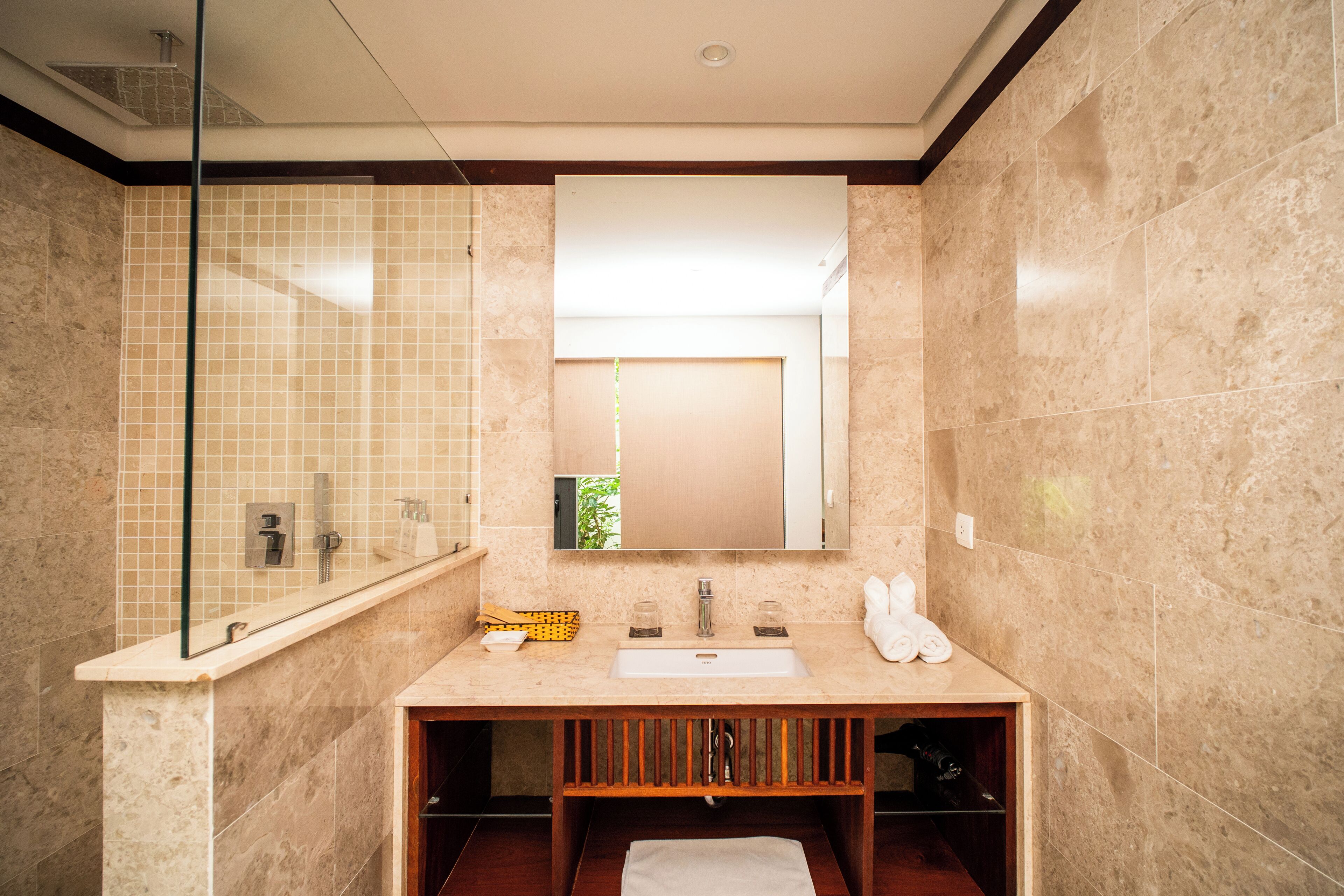 A modern bathroom with a marble sink, glass shower enclosure, and a large mirror.