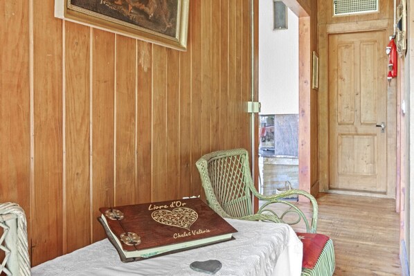 A wooden room with a bed, a wicker chair, and a book titled 'Chalet Valérie'.
